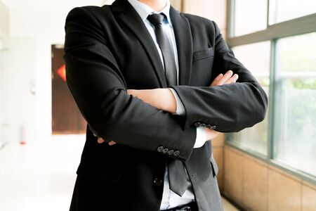 Businessman is standing with his arm crossed blurred backgroundの写真素材