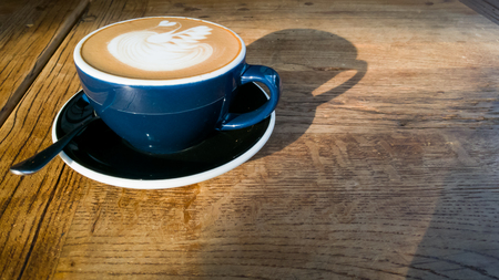 Hot mocha coffee or cappuccino in the blue cup with luxury pattern on the wooden tableの写真素材