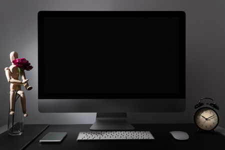 under exposure of retina display with keyboard, mouse, smart phone, alarm clock, wood man and purple carnationの写真素材