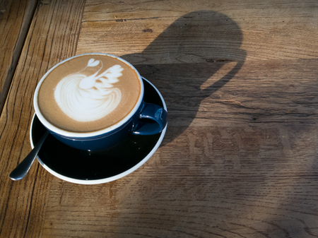 Hot mocha coffee or cappuccino in the blue cup with luxury pattern on the wooden tableの写真素材