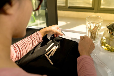 tailor woman taking measure the pattern on the black cloth