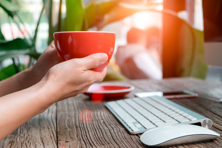 focus on the woman hand holding the coffee at the working table