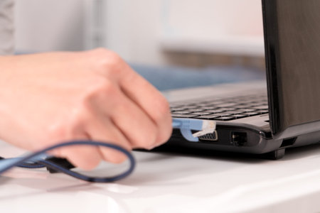 women hand is plugging in the lan cable to laptop port