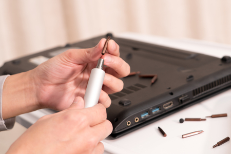 focus on women hand hold the screw driver to repair the laptop, repair and maintenanceの写真素材