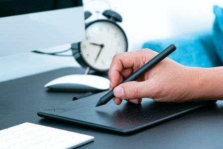 Focus on the busy graphic designer working on computer by digital pen mouse