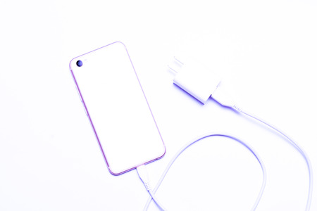 overexposure of the mobile phone pluging in the charger on white backgroundsの写真素材