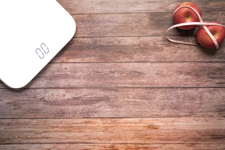 weight scale white digital with diet red apple bind with measuring tape on the wooden backgrounds health and fitness life conceptの写真素材