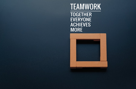 Teamwork concept. group of wooden square on the black backgrounds with word Teamwork, Together, Everyone, Achieves and Moreの写真素材