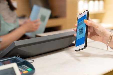 SHANGHAI, CHINA - MAY, 2018 : Qr code payment, online shopping, cashless technology concept. women hand hold the smartphone for payment at shopping centerのeditorial素材