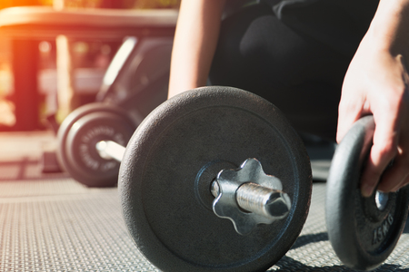 women hand setting the steel dumbbell in a gym musclebuildingの写真素材