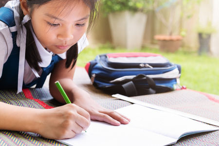 little girl writes to writing-books. The decision of lessons. girl lay down drawing the pictureの写真素材