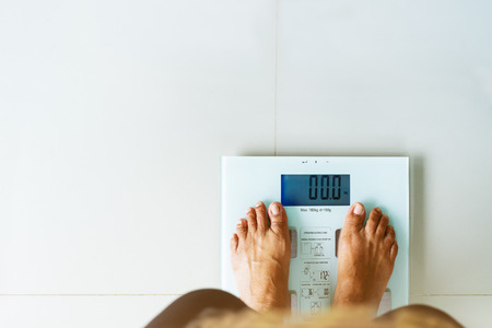 old woman standing on weight scale white colorの写真素材
