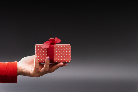 Woman hand give a present on black background, Christmas Boxing Day conceptの写真素材