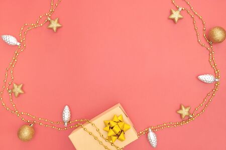 gift box or present box with golden star, bell and ball on pink living coral background for birthday, christmas or wedding ceremonyの写真素材