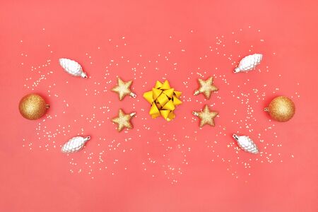 golden bow, star, bell and ball on pink living coral background for birthday, christmas or wedding ceremonyの写真素材