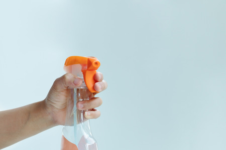 woman hand hold a spray of cleaning fluid on blue backgroundの写真素材