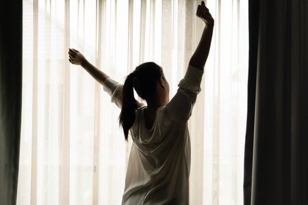 Woman stretching in bedroom after wake up, back viewの写真素材