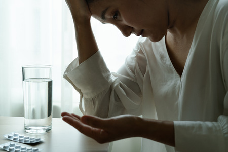 headache women hand hold medicine with a glass of water, healthcare and medicine recovery conceptの写真素材