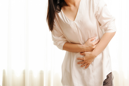 Young woman suffering from abdominal pain feeling stomachache, symptom of pms on white backgroundの写真素材