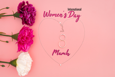 International Womenâs Day with flowers and heart shape necklace on pink backgroundの写真素材