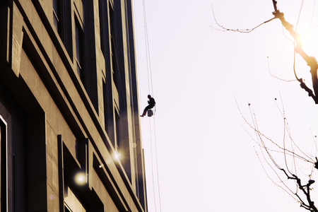 worker cleaning outdoor windows service on high rise buildingの写真素材