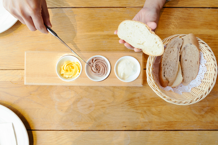 Woman hand spreading butter on sliced breadの写真素材