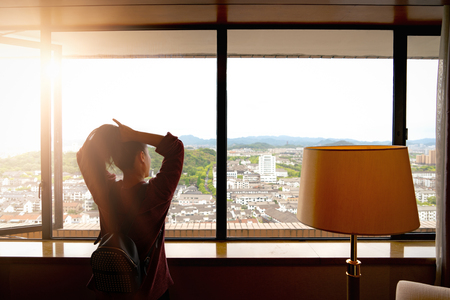 Woman tight hair ready while looking at view from windowの写真素材