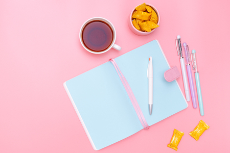 workspace desk styled design office supplies, hot tea and candy on pink pastel background minimal styleの写真素材
