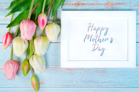 Happy mother's day concept. white picture frame and flower on wooden backgroundの写真素材