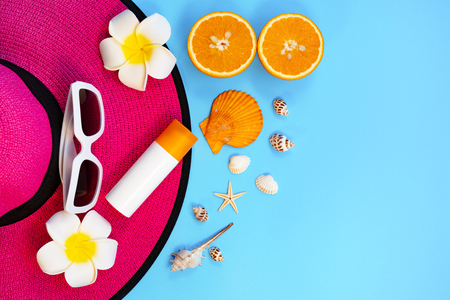 Beautiful summer holiday, Beach accessories, sunglasses, hat, orange, sunblock and shells on blue backgroundの写真素材
