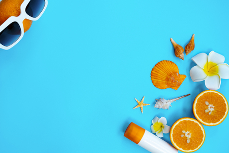 Beautiful summer holiday, Beach accessories, orange, shells and sunblock on blue backgroundの写真素材