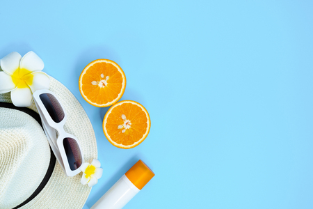Beautiful summer holiday, Beach accessories, sunglasses, hat, orange and sunblock on blue backgroundの写真素材