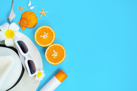 Beautiful summer holiday, Beach accessories, sunglasses, hat, orange, sunblock and shells on blue backgroundの写真素材