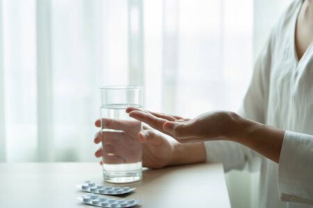 depressed women hand hold medicine with a glass of water, healthcare and medicine recovery conceptの写真素材