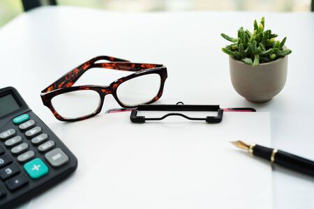 Business objects, clipboard with blank sheet of paper, pen, glasses and calculator on white backgroundの写真素材