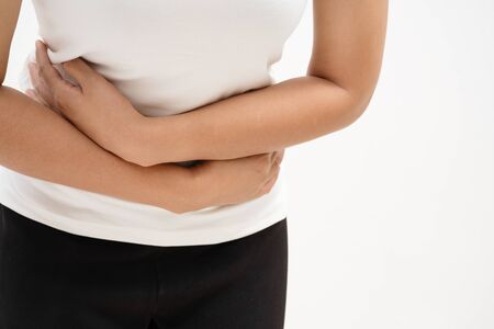 Young woman suffering from abdominal pain feeling stomachache, symptom of pms on white backgroundの写真素材