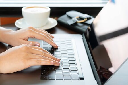 woman hands typing on laptop keyboard. Woman working at office with coffeeの写真素材