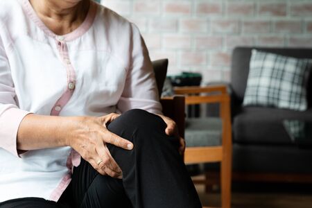 senior woman suffering from knee pain at home, health problem conceptの写真素材