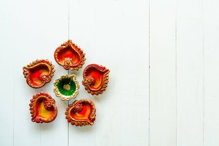 Happy Diwali - Clay Diya lamps lit during Dipavali, Hindu festival of lights celebration. Colorful traditional oil lamp diya on white wooden backgroundの写真素材