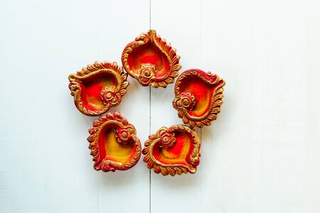 Happy Diwali - Clay Diya lamps lit during Dipavali, Hindu festival of lights celebration. Colorful traditional oil lamp diya on white wooden backgroundの写真素材