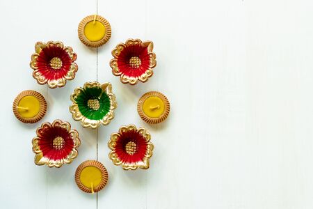 Happy Diwali - Clay Diya lamps lit during Dipavali, Hindu festival of lights celebration. Colorful traditional oil lamp diya on white wooden backgroundの写真素材