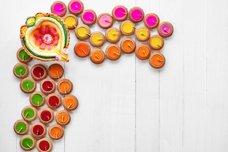 Happy Diwali - Clay Diya lamps lit during Dipavali, Hindu festival of lights celebration. Colorful traditional oil lamp diya on white wooden backgroundの写真素材