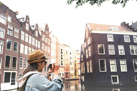 Outdoor lifestyle portrait of pretty young woman having fun in the city in Europe with digital camera travel photo of photographer Making pictures in hipster styleの写真素材