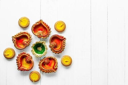 Happy Diwali - Clay Diya lamps lit during Dipavali, Hindu festival of lights celebration. Colorful traditional oil lamp diya on white wooden backgroundの写真素材