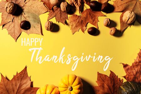 Happy Thanksgiving Day with maple leaves, nut and pumpkin on yellow backgroundの写真素材