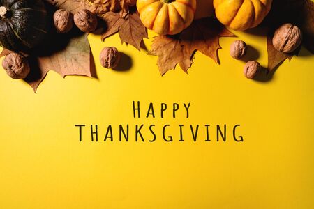Happy Thanksgiving Day with maple leaves, nut and pumpkin on yellow backgroundの写真素材
