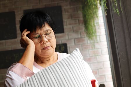Frustrated older mature woman feeling boring desperate looking on the smartphone, stressed sad middle aged female depressed by hearing bad newsの写真素材