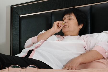 senior woman with headhache dizziness and smelling saltsの写真素材