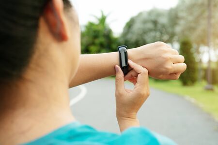 fitness woman runner setting up smart watch before running. Outdoor exercise activitiesの写真素材