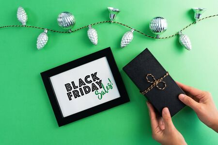 hand holding gift box with photo frame for Black Friday Sale concept on green backgroundの写真素材